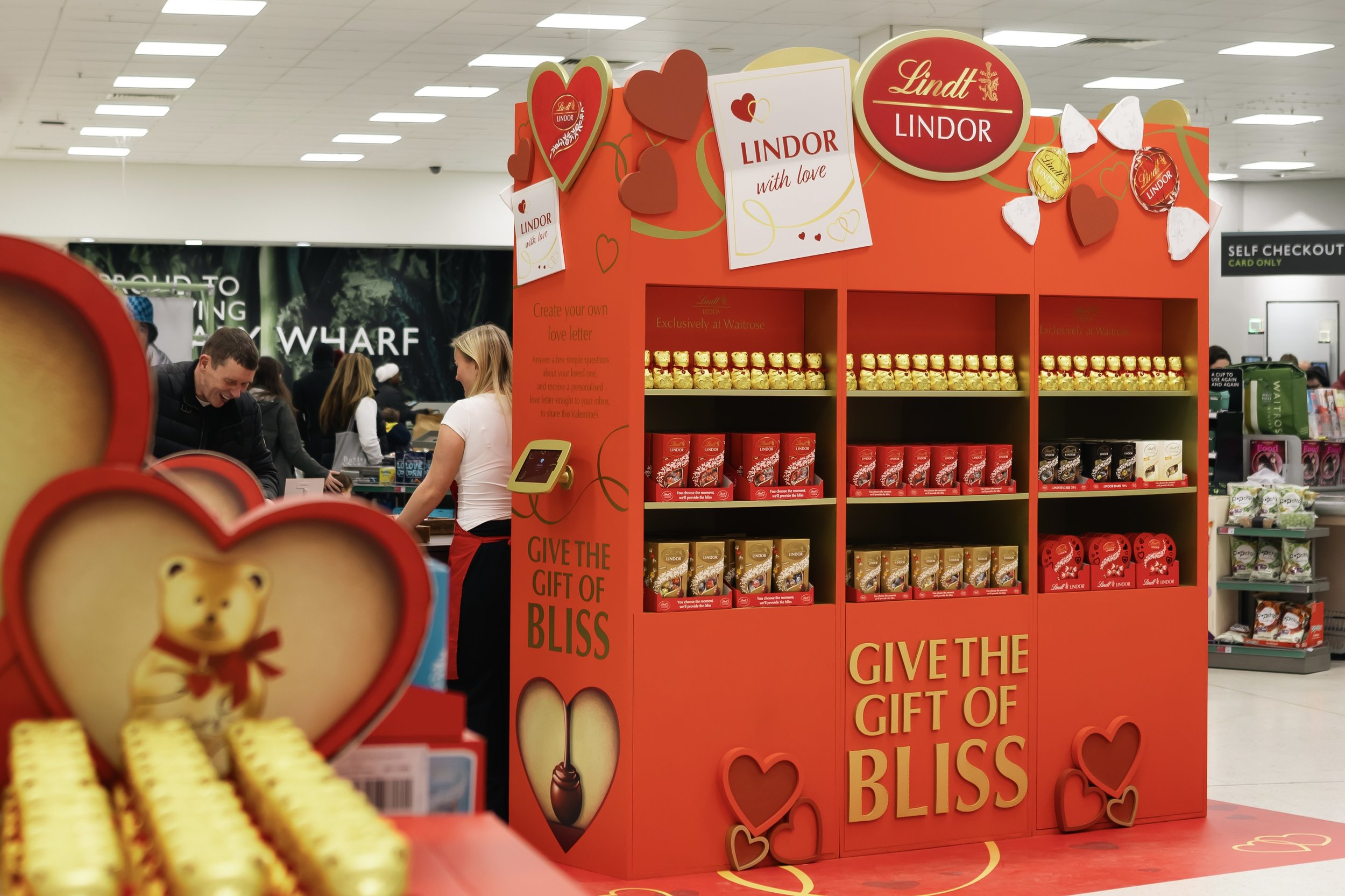 Lindt Valentine's Day chocolate display in Waitrose with rows of chocolate boxes on a red stand that says 'Give the gift of bliss'