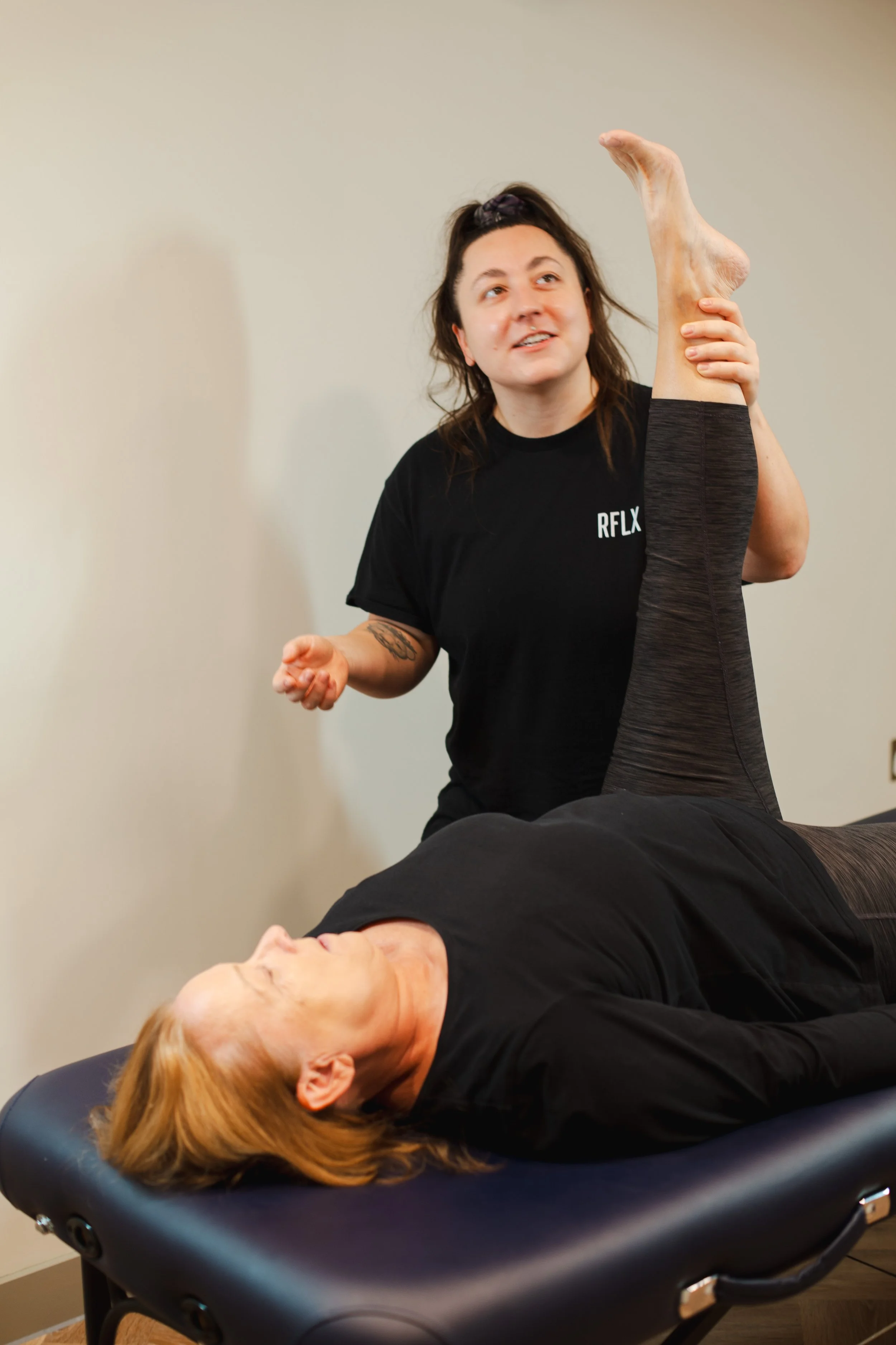 Sports massage therapist testing hamstring flexibility during a clinic assessment