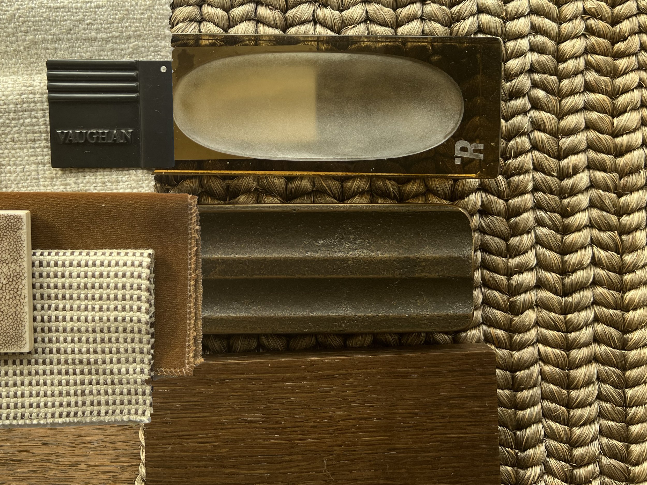 Sophisticated material selection with bronze, stone, velvety fabrics, and natural wood on a woven surface.