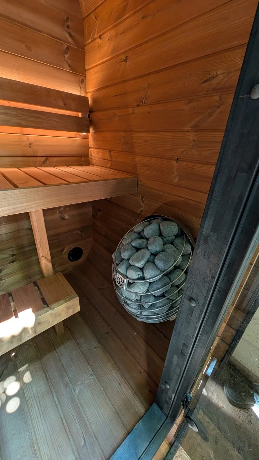 Finished benches, vent, and HUUM DROP — handover-ready interior.