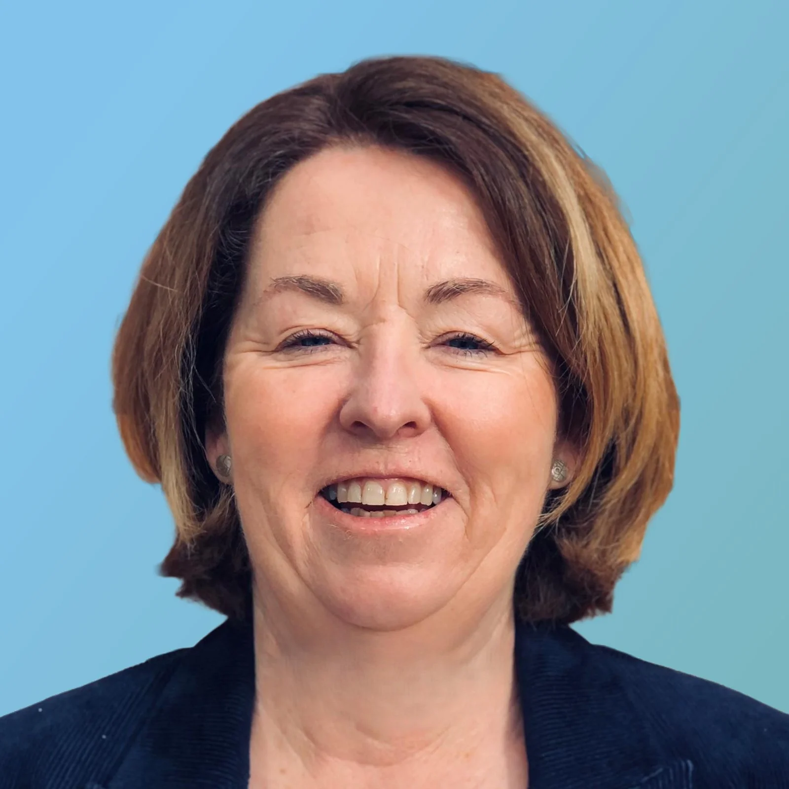 A woman with short, brown hair smiling against a blue background.