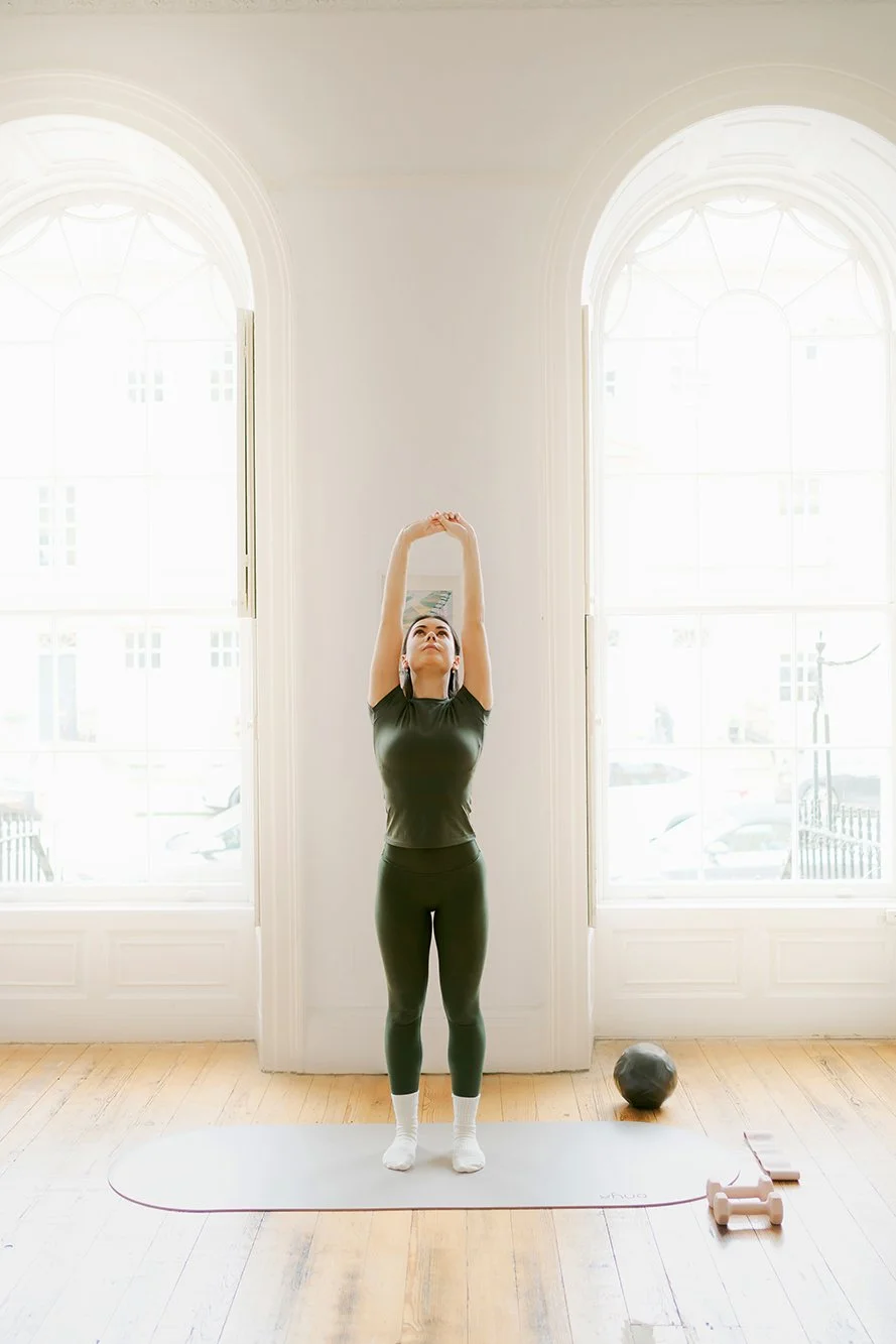 Personal branding photographer in Bath - image of a woman doing pilates, stretching her arms into the air.