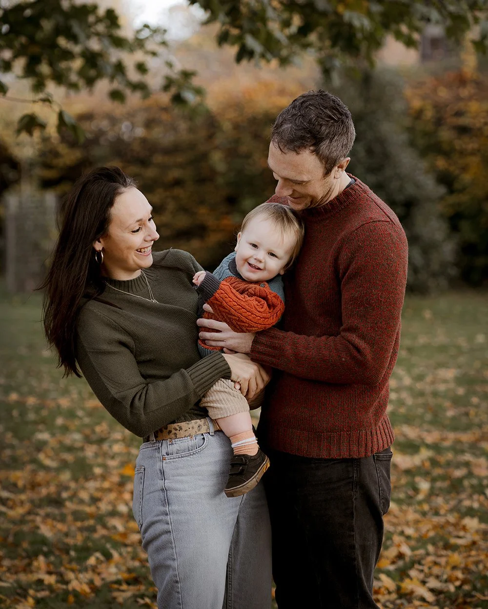 Parents holding their toddler between them during an outdoor family photoshoot in Bristol.