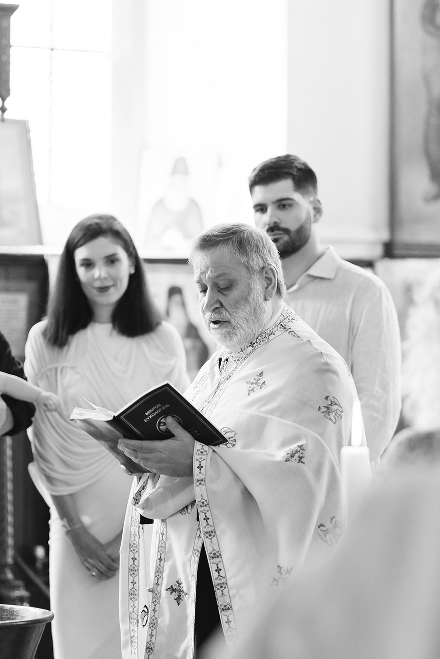 Christening photographer Bristol - Image of a priest during a baptism ceremony in Bristol.