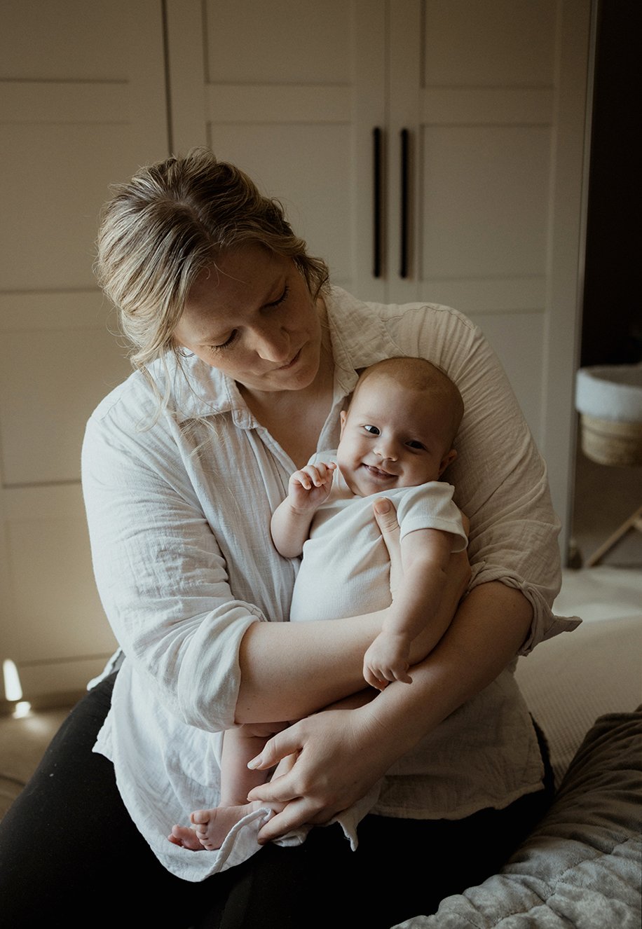 Newborn photographer Bristol - image of a mother holding her baby who is smiling.