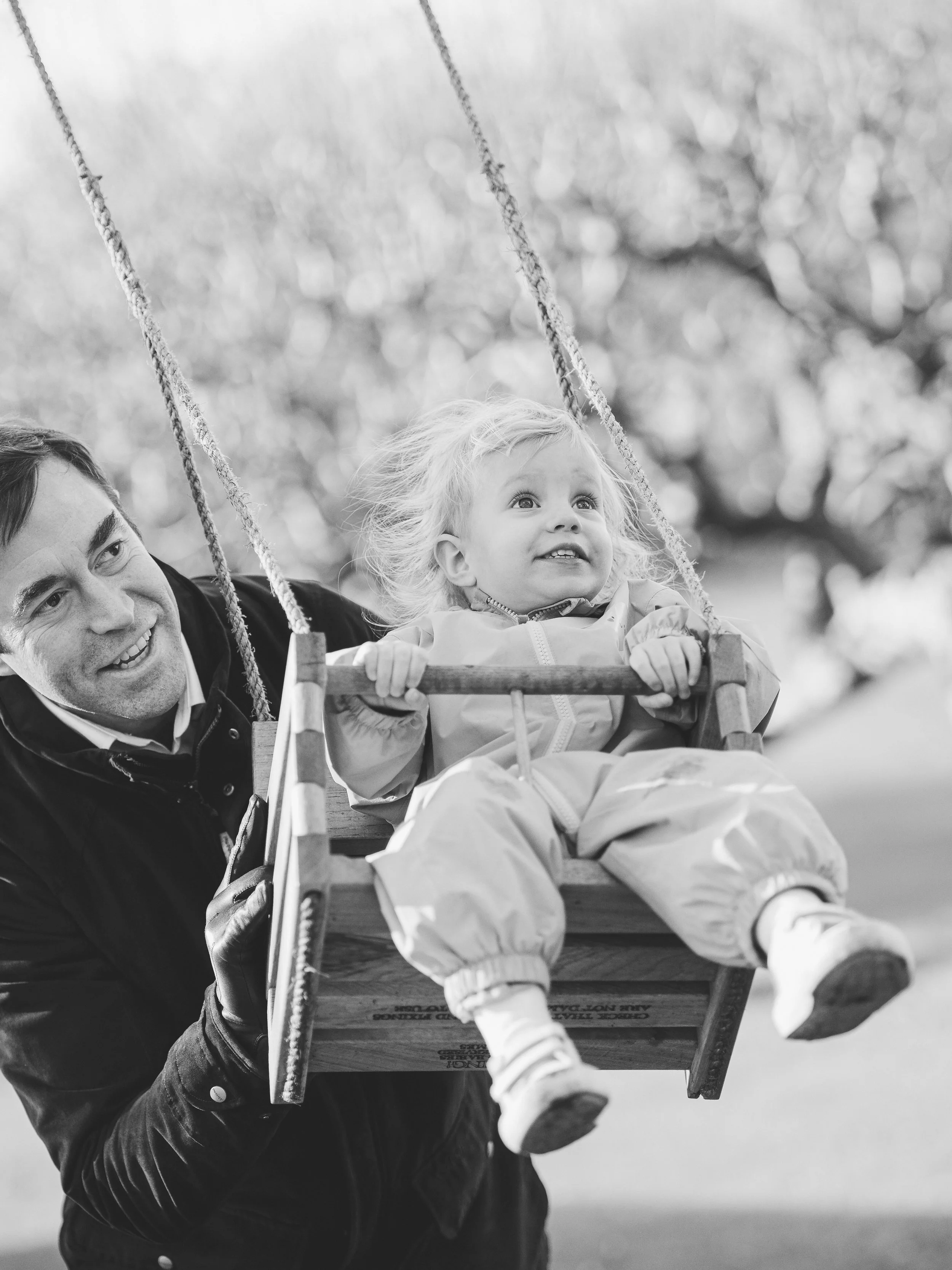 Family photographer Bath - image of a father pushing his little girl on a swing during a family photoshoot in Bath.