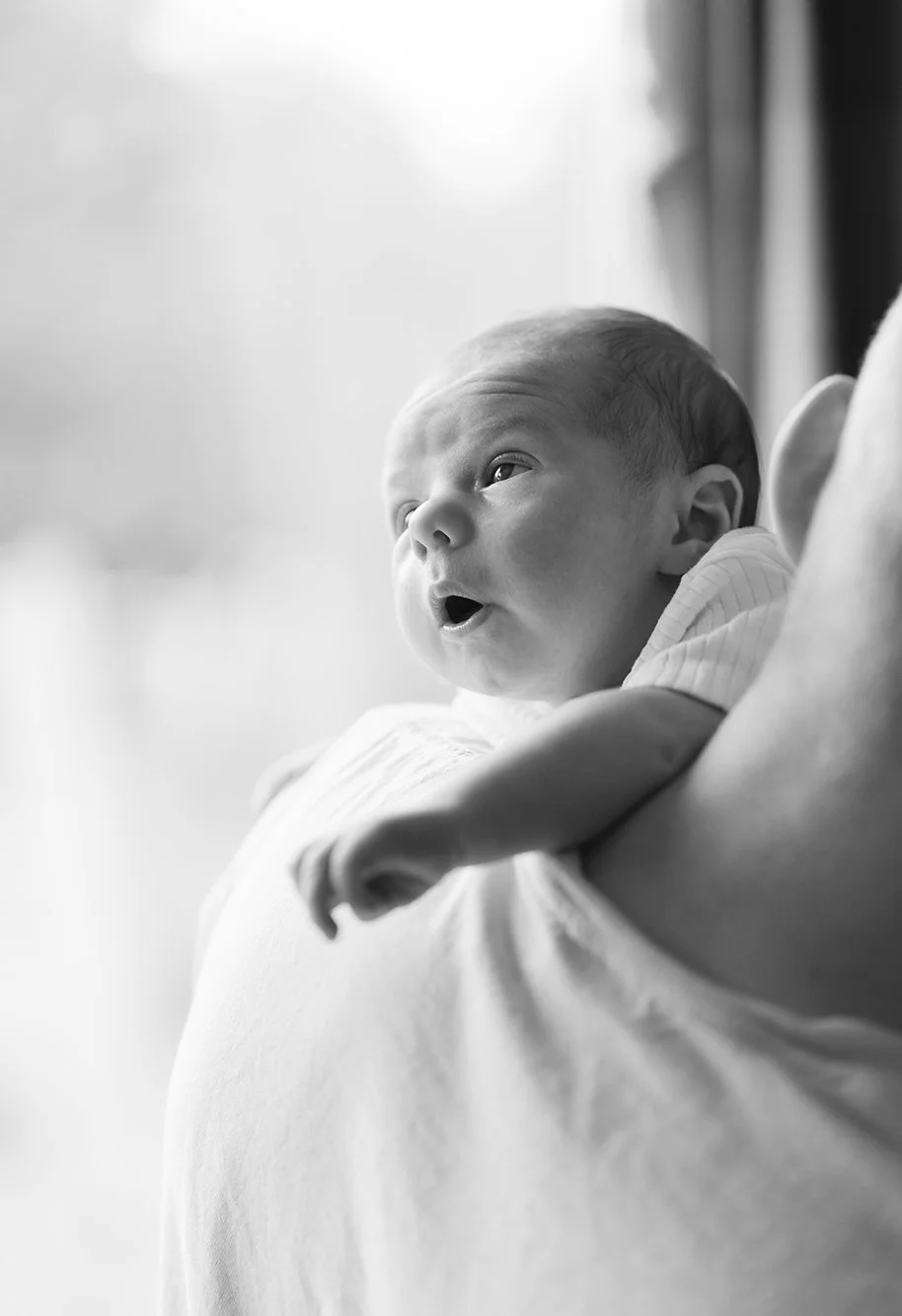 Baby photographer Somerset - image of a baby looking out a window during a photoshoot at home