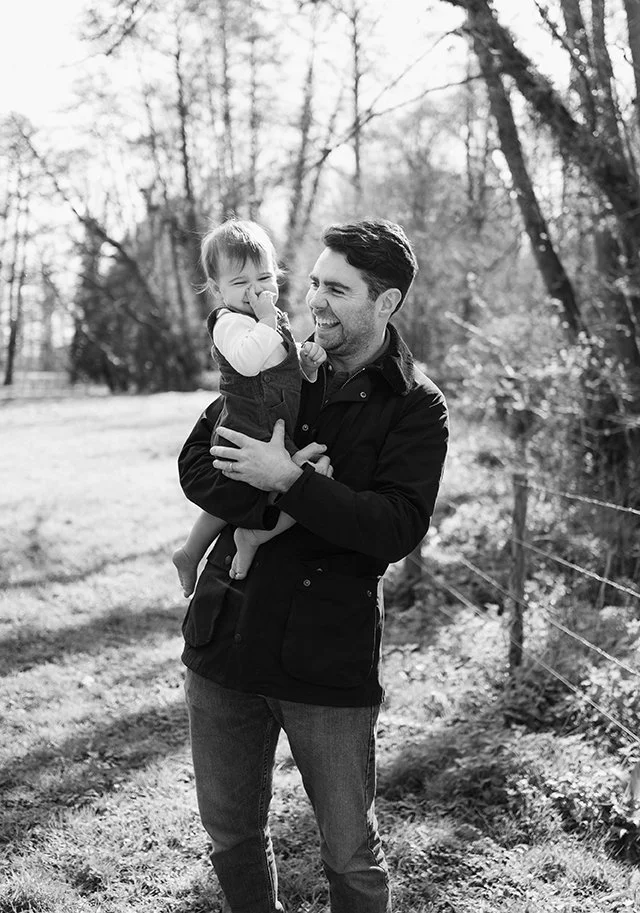 Black and white image of a father carrying his little boy during a family photoshoot.