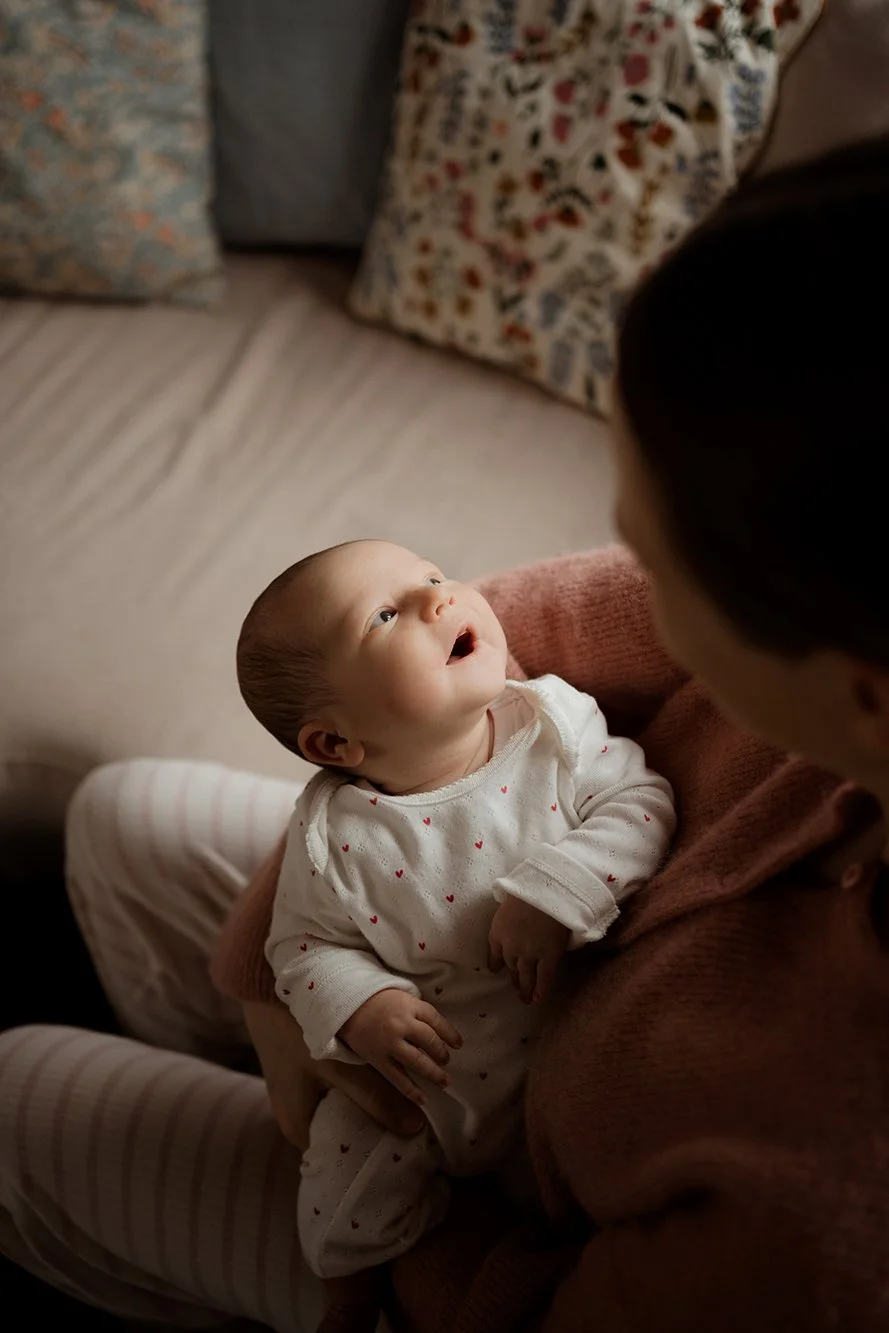 Newborn and baby photographer Bristol - image of a baby looking up and being held by his mother during a photoshoot.