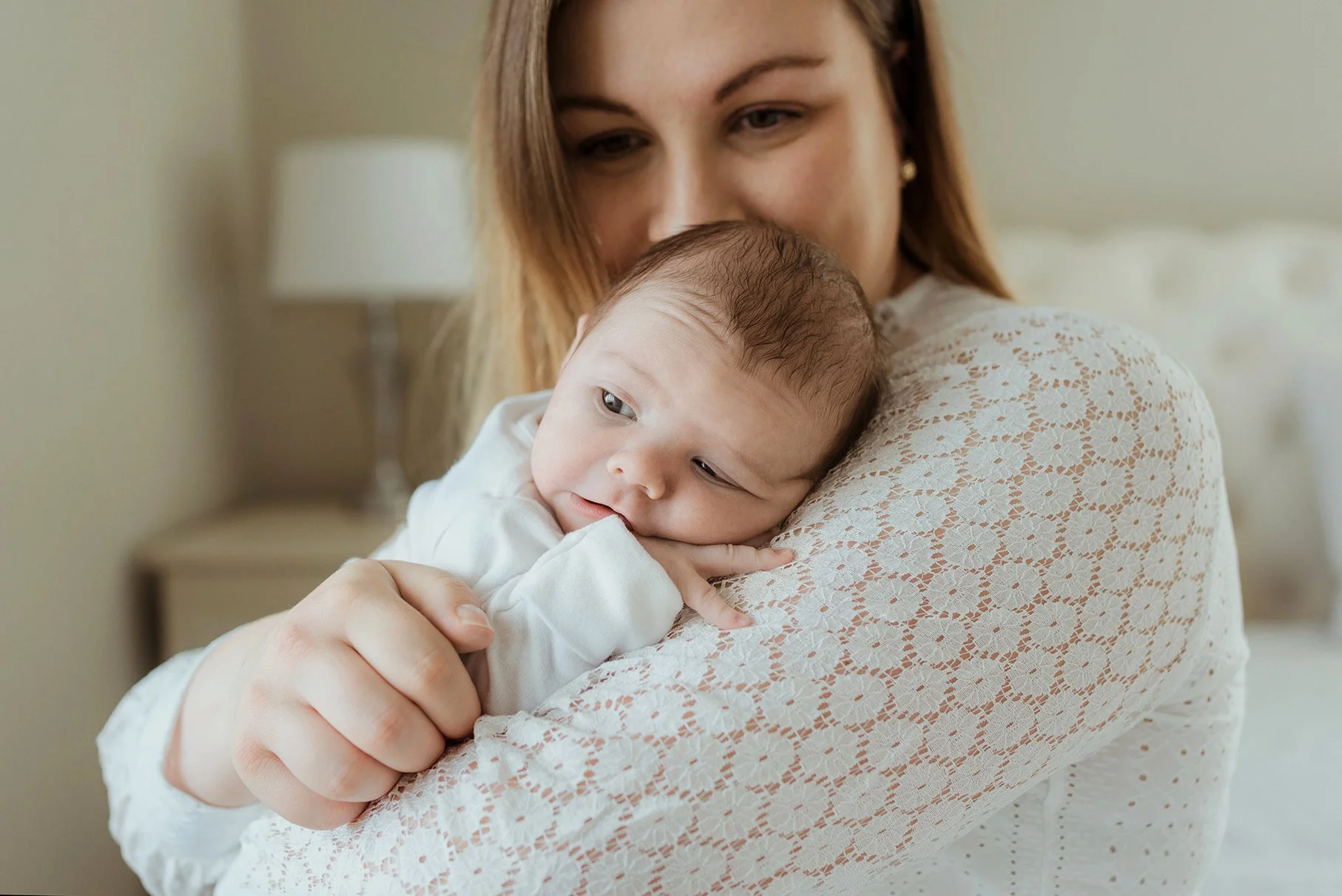 Bath newborn and baby photographer - image of a mother holding her baby during a photoshoot in their own home in Bath.