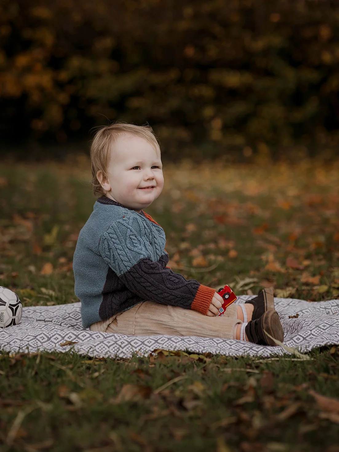 Portrait of a one year old boy sitting on a blanket during an outdoor family photoshoot in Bristol.