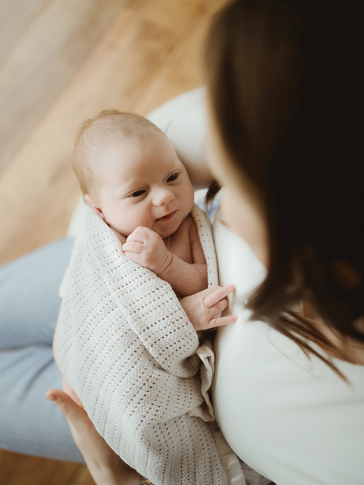 Mother holding her newborn baby as they look into each other’s eyes during a relaxed at-home photoshoot near Bath - Bath newborn photographer