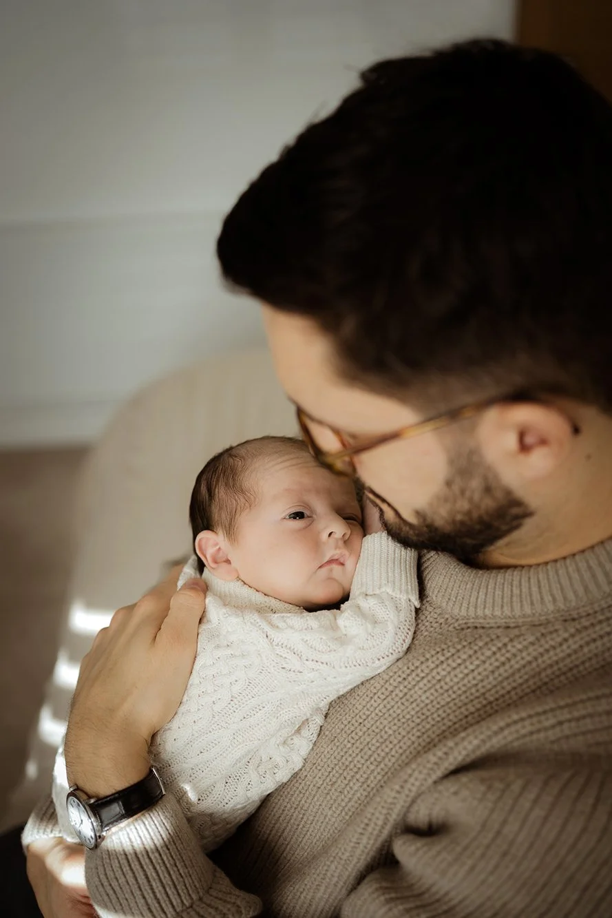 Newborn and baby photographer - image of a newborn reasting on father's shoulder.