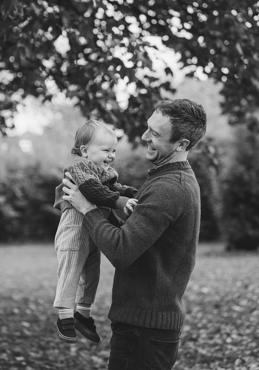 Father lifting his little son up as he laughs during a family photoshoot in Henleaze.