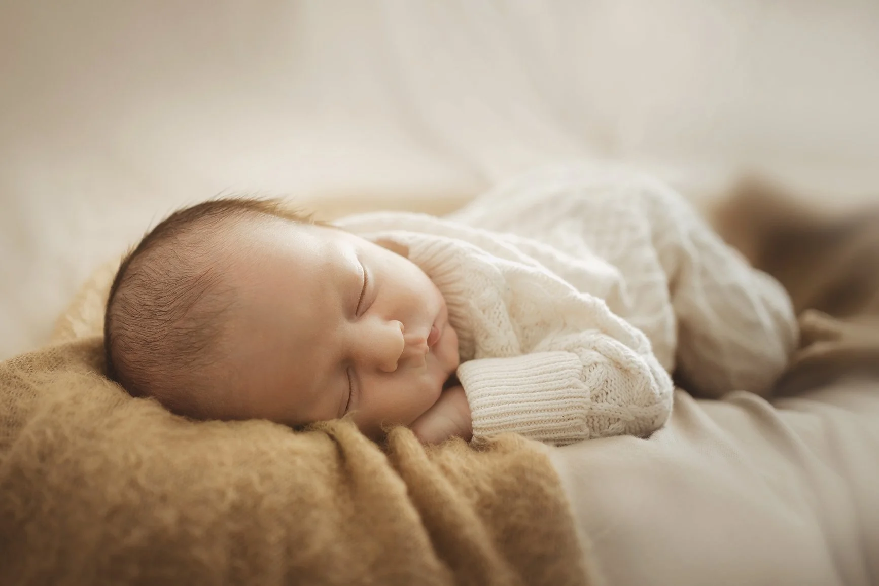 Newborn and baby photographer - image of a newborn baby sleeping on a soft blanket during a photoshoot.