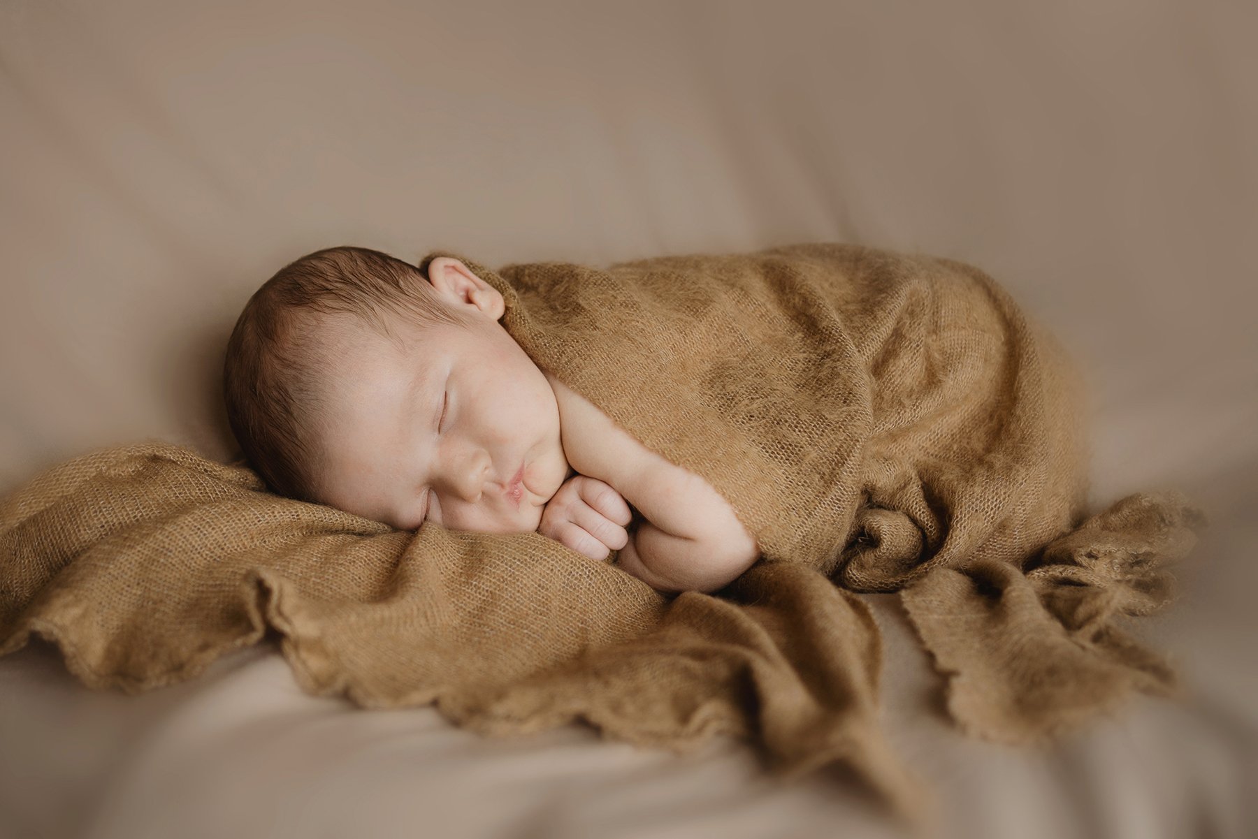 Newborn and baby photographer Bristol - image of a newborn abby sleeping wrapped in a blanket during a photoshoot.