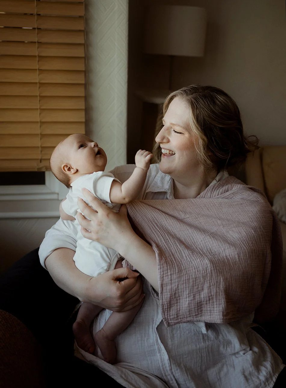 Newborn photographer Bristol - image of a mother holding her baby and laughing..