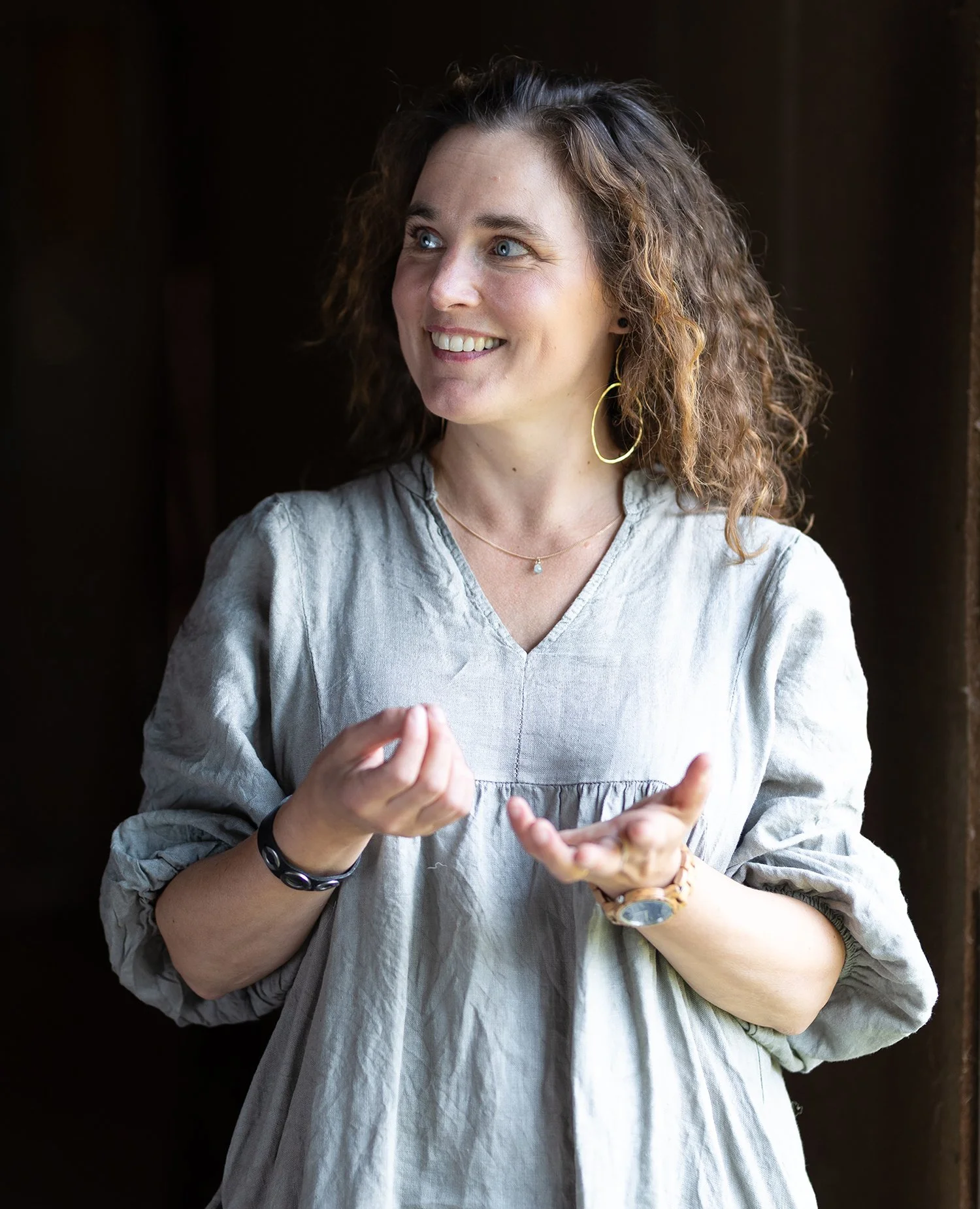 Nainen hymyilee ja katsoo sivulle päin ja elehtii käsillään.