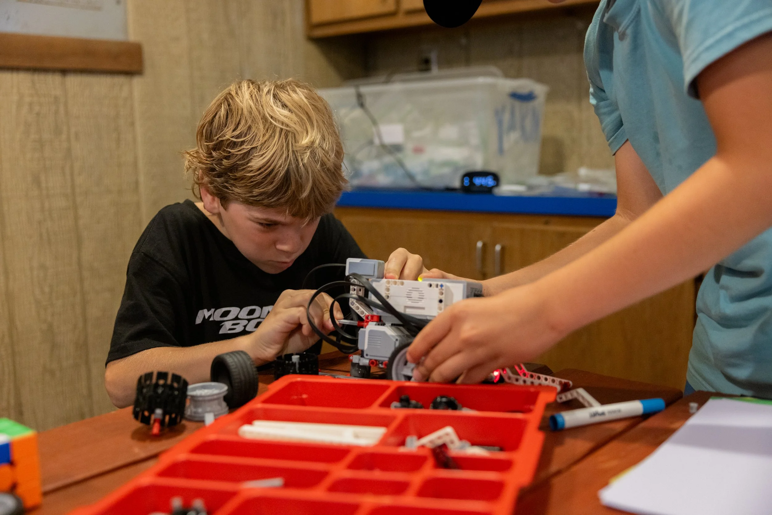 Two children working on assembling a robot with Lego Mindstorms on a table.