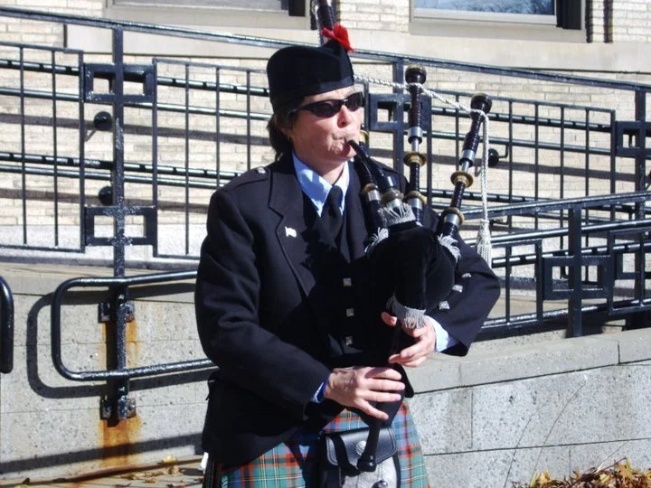 Person in a uniform playing bagpipes outdoors
