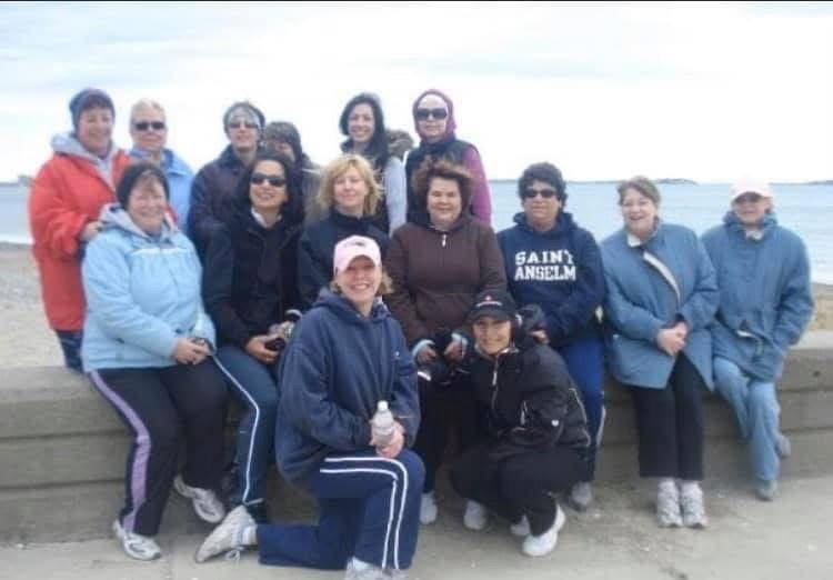 Group of people posing outdoors on a seaside promenade with water and sky in the background.