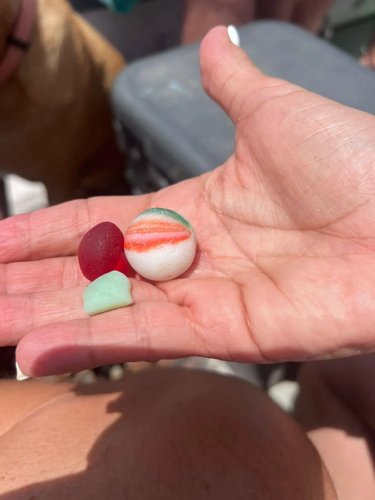 Hand holding three colorful marbles, with a blurred background.
