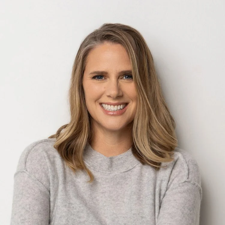 Kristen Arterburn is a woman with shoulder-length blonde hair smiling and wearing a light gray sweater, standing against a plain white background.