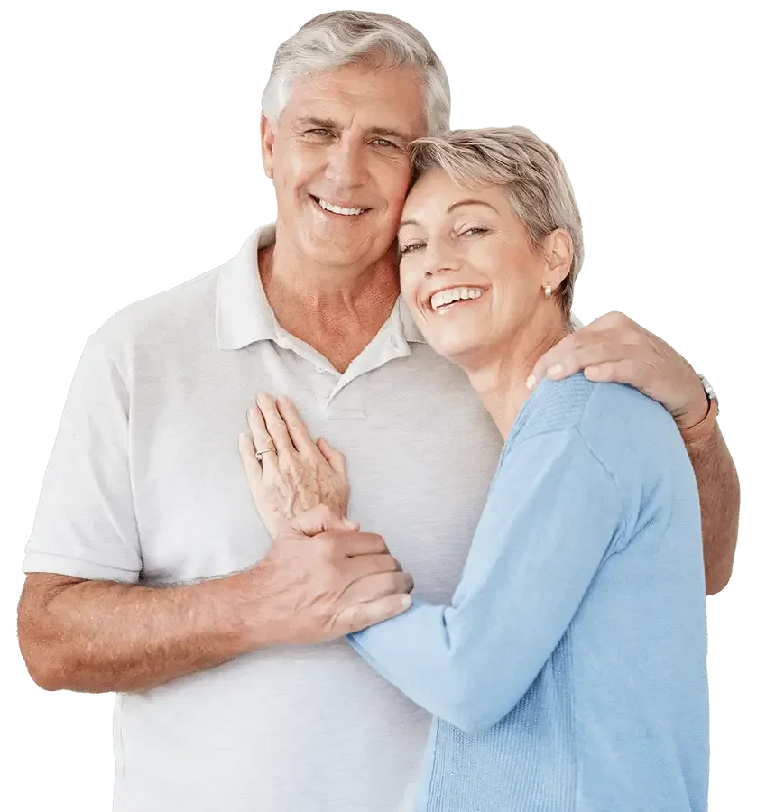 An elderly couple hugging and smiling, the man wearing a white polo shirt, the woman in a light blue blouse.