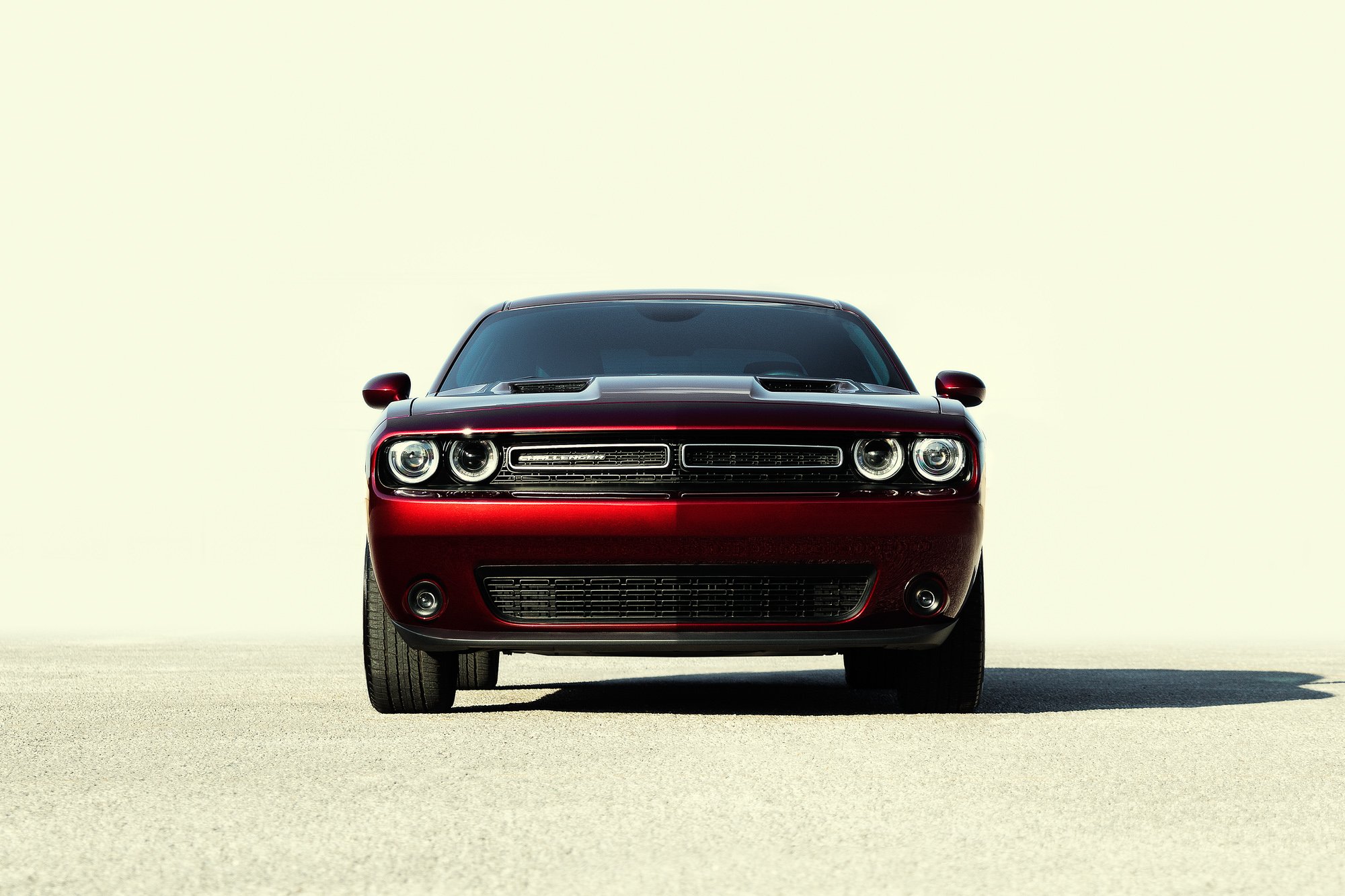 Front view of a red Dodge Challenger car on a flat, light-colored surface with a plain light background.