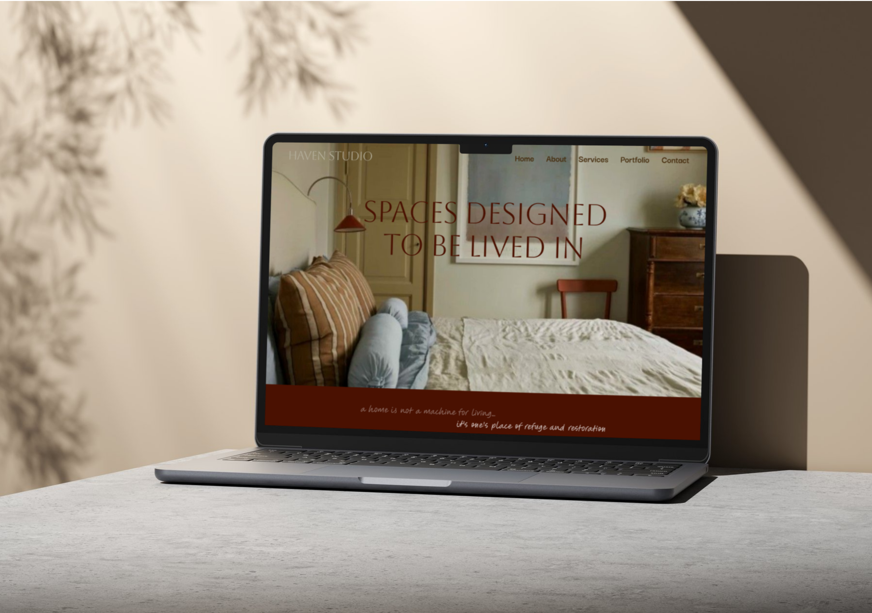 Laptop on a table displaying the homepage of Haven Studio's website, a case study by Hailey Osborne Designs about interior design, with a bedroom scene featuring a bed, pillows, and furniture in the background.