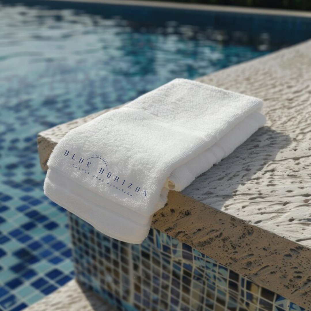 White towel folded on a stone ledge next to a swimming pool with blue mosaic tiles, with the Blue Horizons pool company logo, a web design and branding case study by Hailey Osborne Designs.