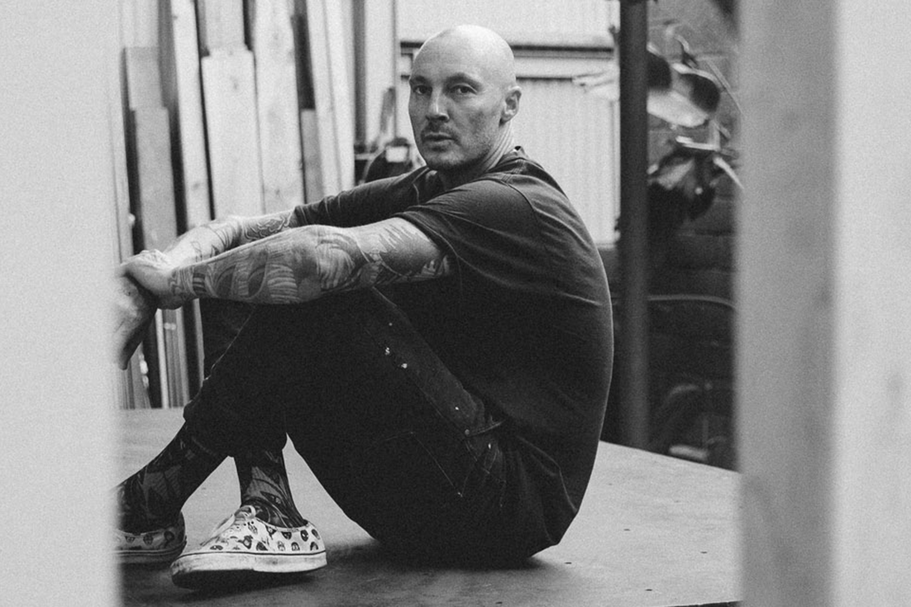 artist griffin loop in black and white looking at the camera sitting down holding his knees