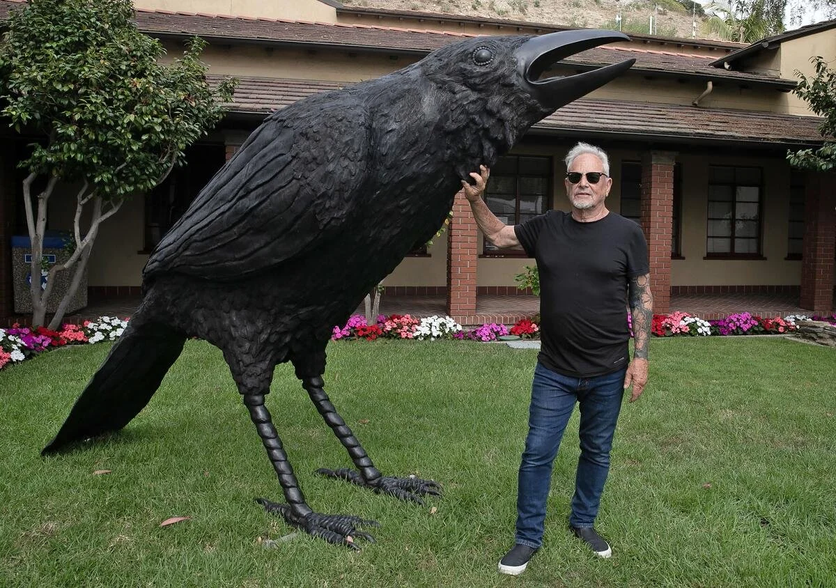 Artist jack champion standing next to a giant crow sculpture