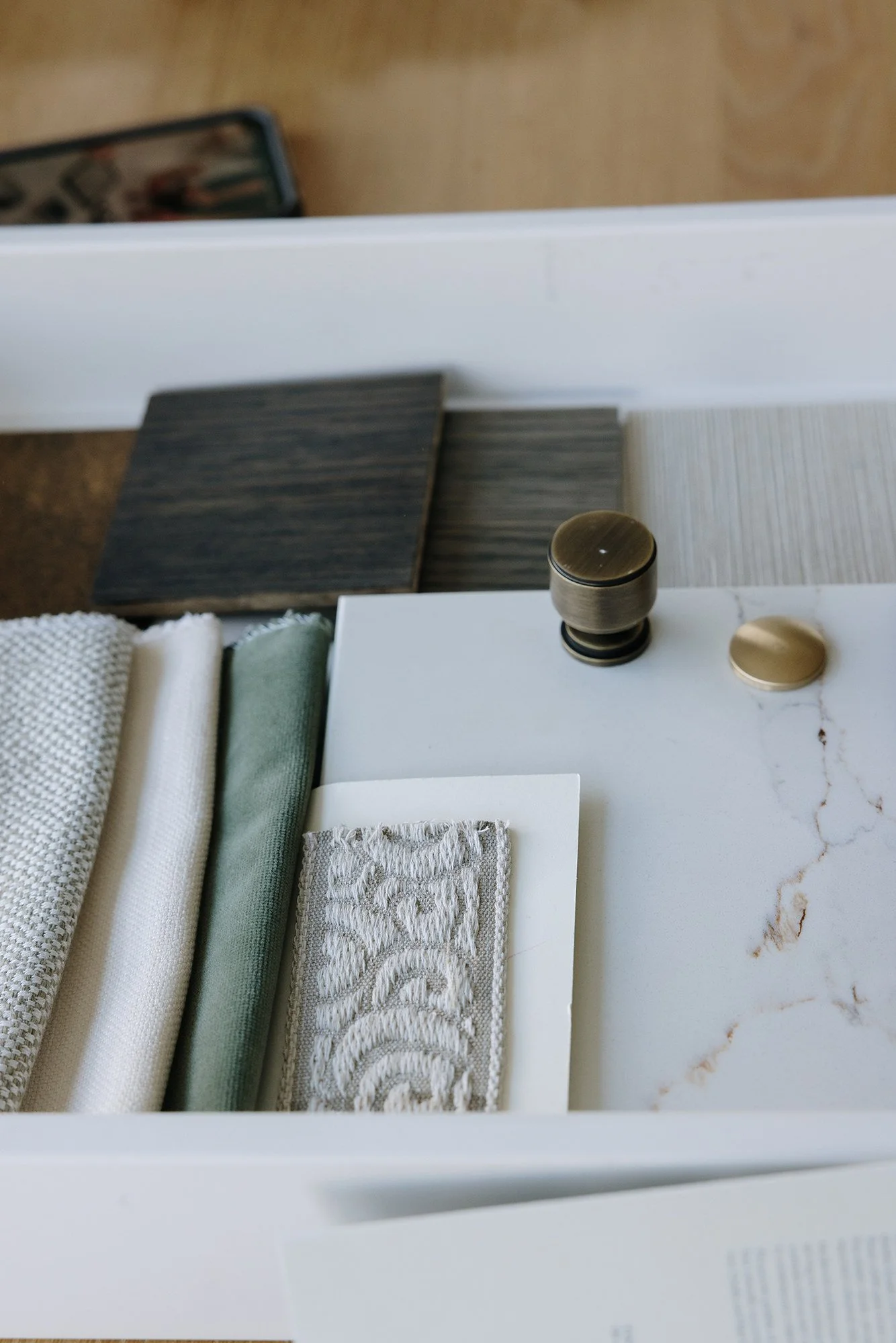 A closet showing fabric samples, color swatches, and hardware knobs on a marble surface.