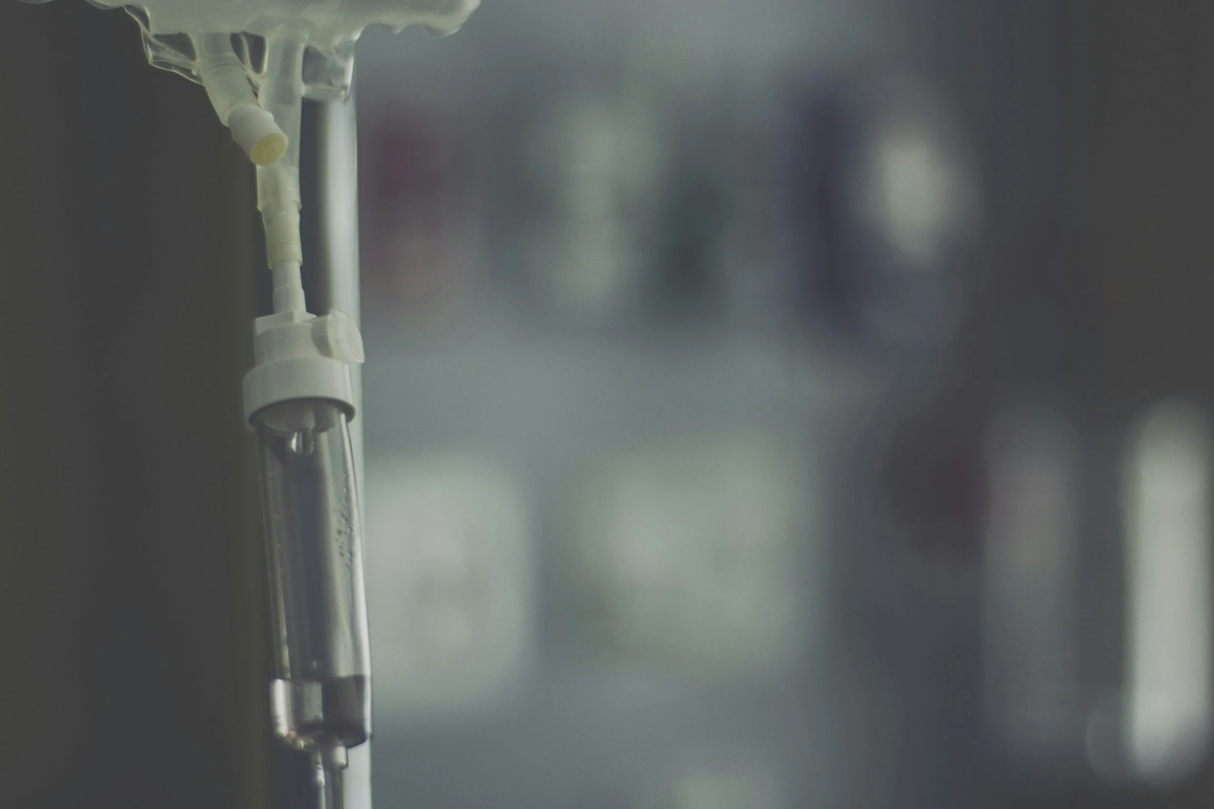 Close-up of an intravenous (IV) drip hanging from a pole in a hospital setting.