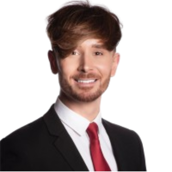 Professional man with brown hair, beard, wearing a suit and red tie, smiling at camera