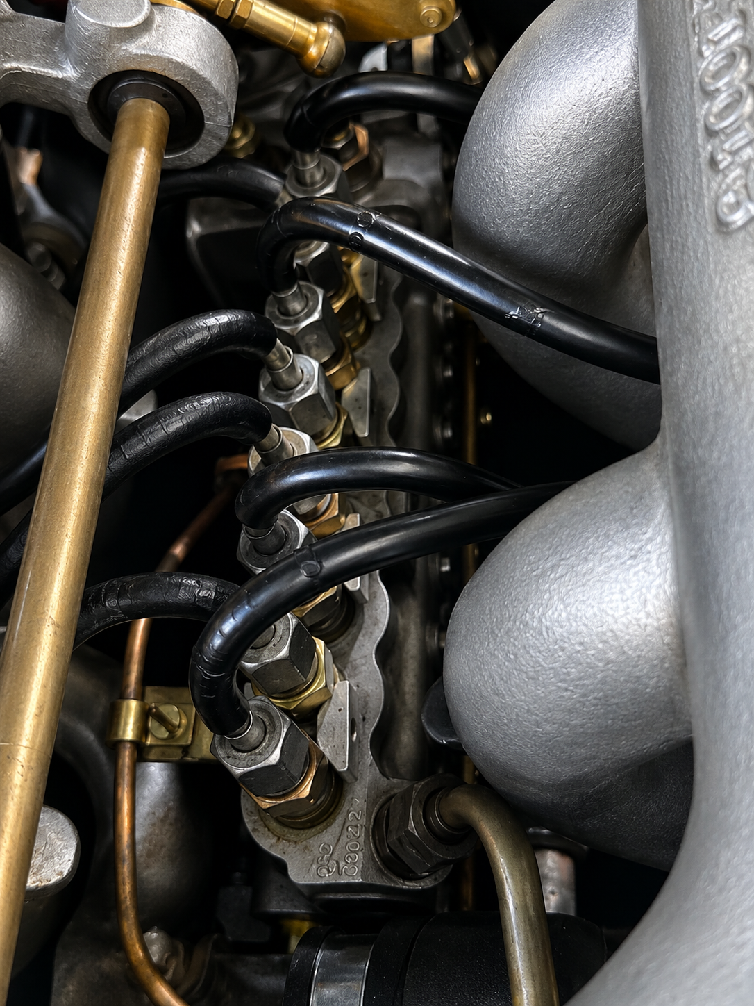 Close-up view of an internal engine component with metal and black hoses connected to a metal plate.