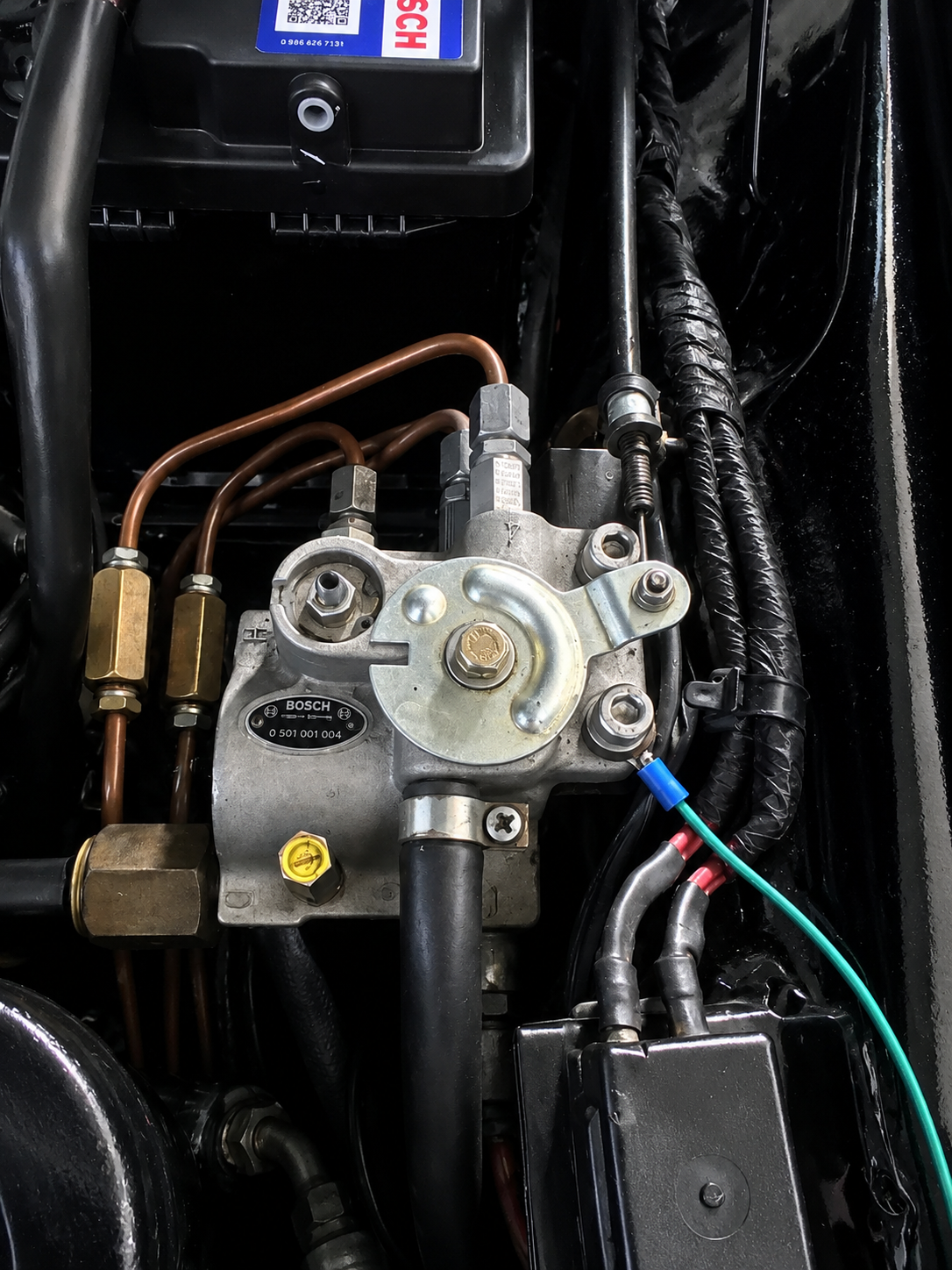 Close-up view of a mechanical component with copper pipes, metal fittings, and wiring, part of an engine or machinery system.