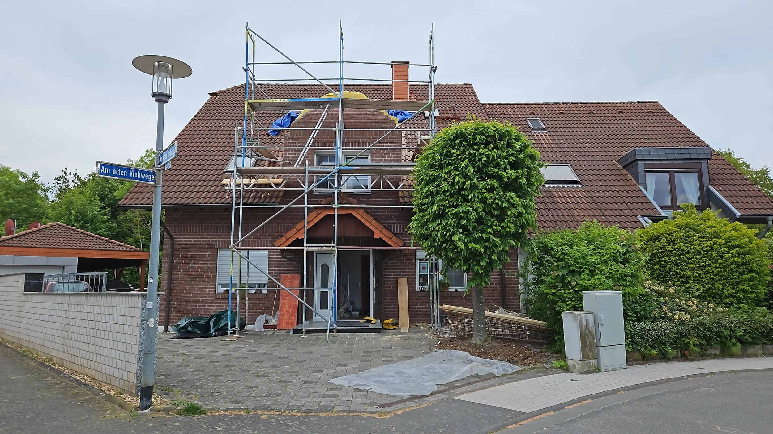 Ein Haus mit Gerüst vor der Haustür, während Arbeiten an der Fassade durchgeführt werden, um einen Dachschmuck zu reparieren oder zu erneuern.