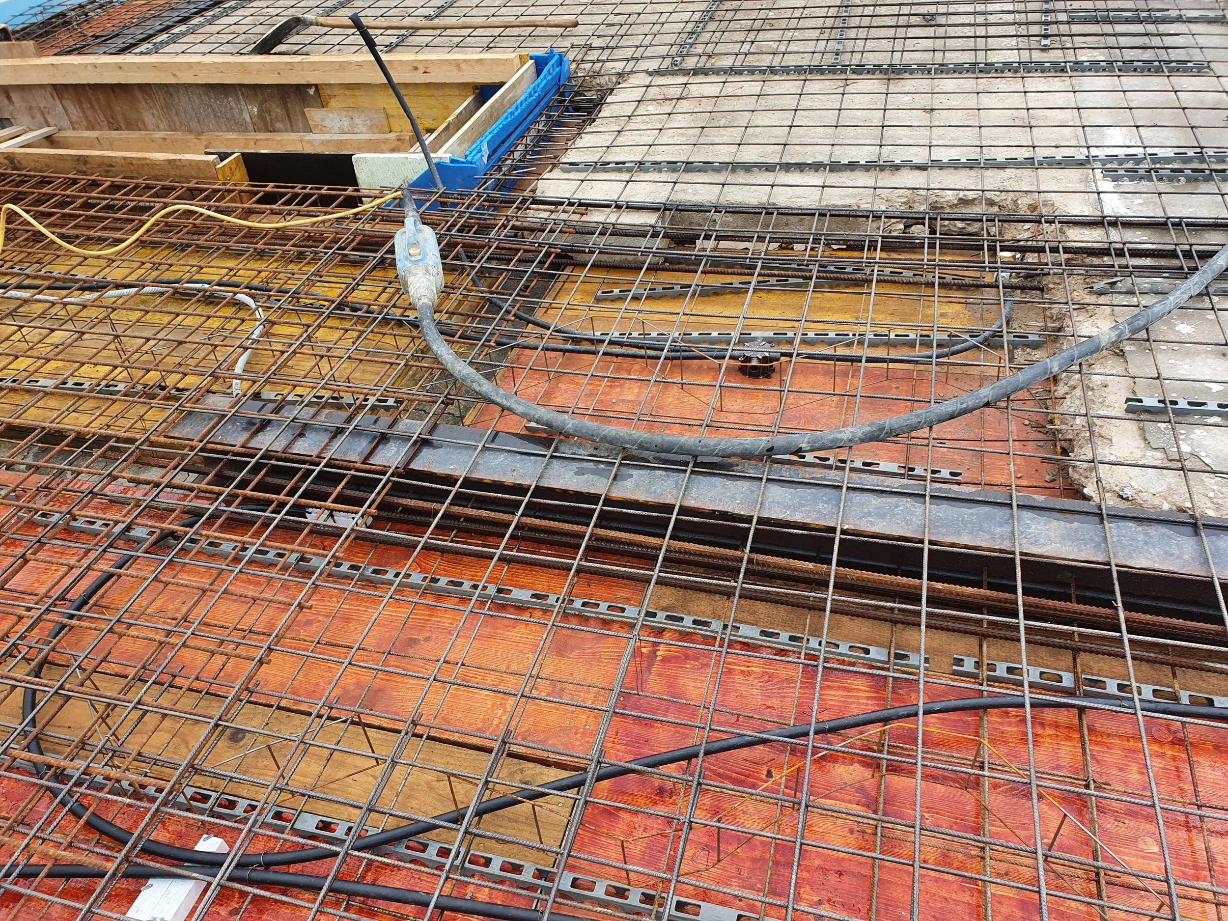 Baustellenstahlarmierung und elektrische Kabel auf einer Bauplatte.