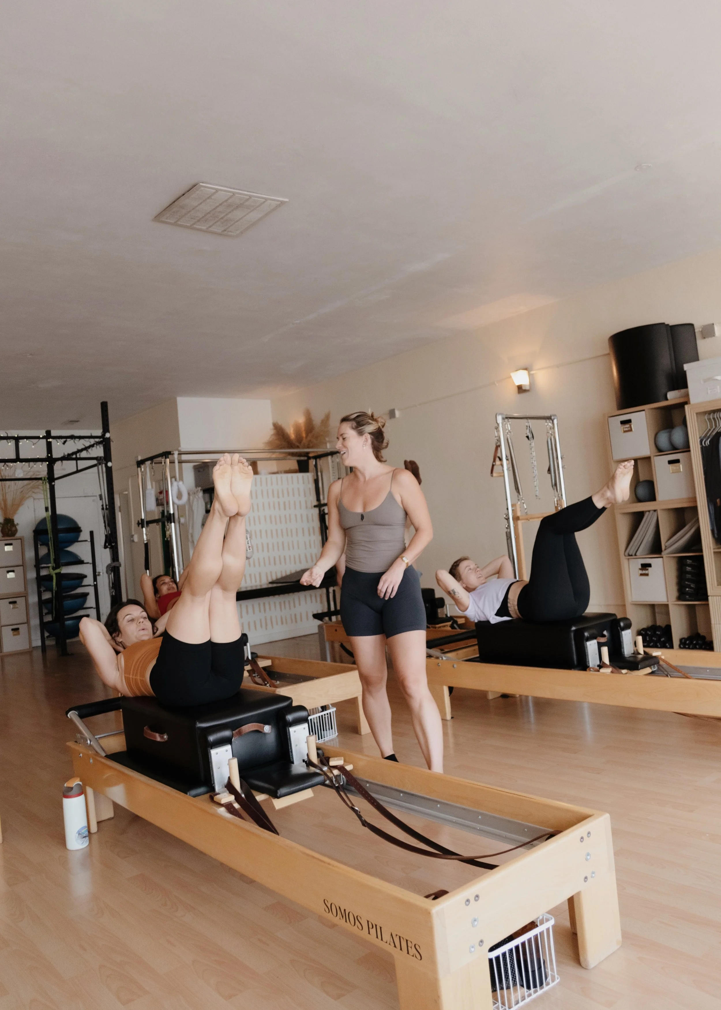 Somos Pilates instructor guiding a client through a Pilates exercise.