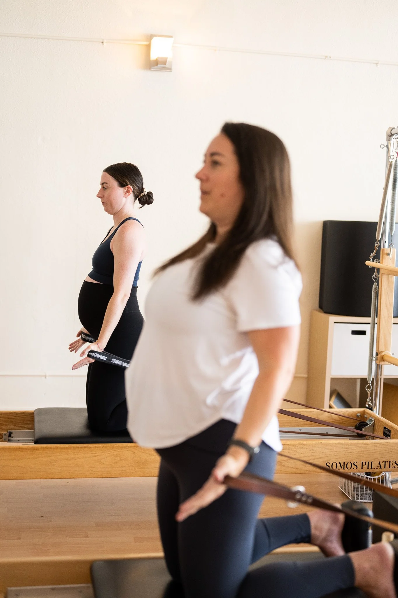 Two pregnant women practicing Pilates at Somos Pilates.