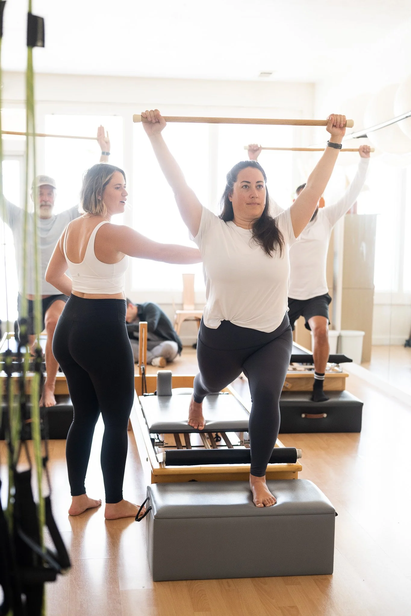 Pilates instructor Meredith guiding a student to correct her posture and form.