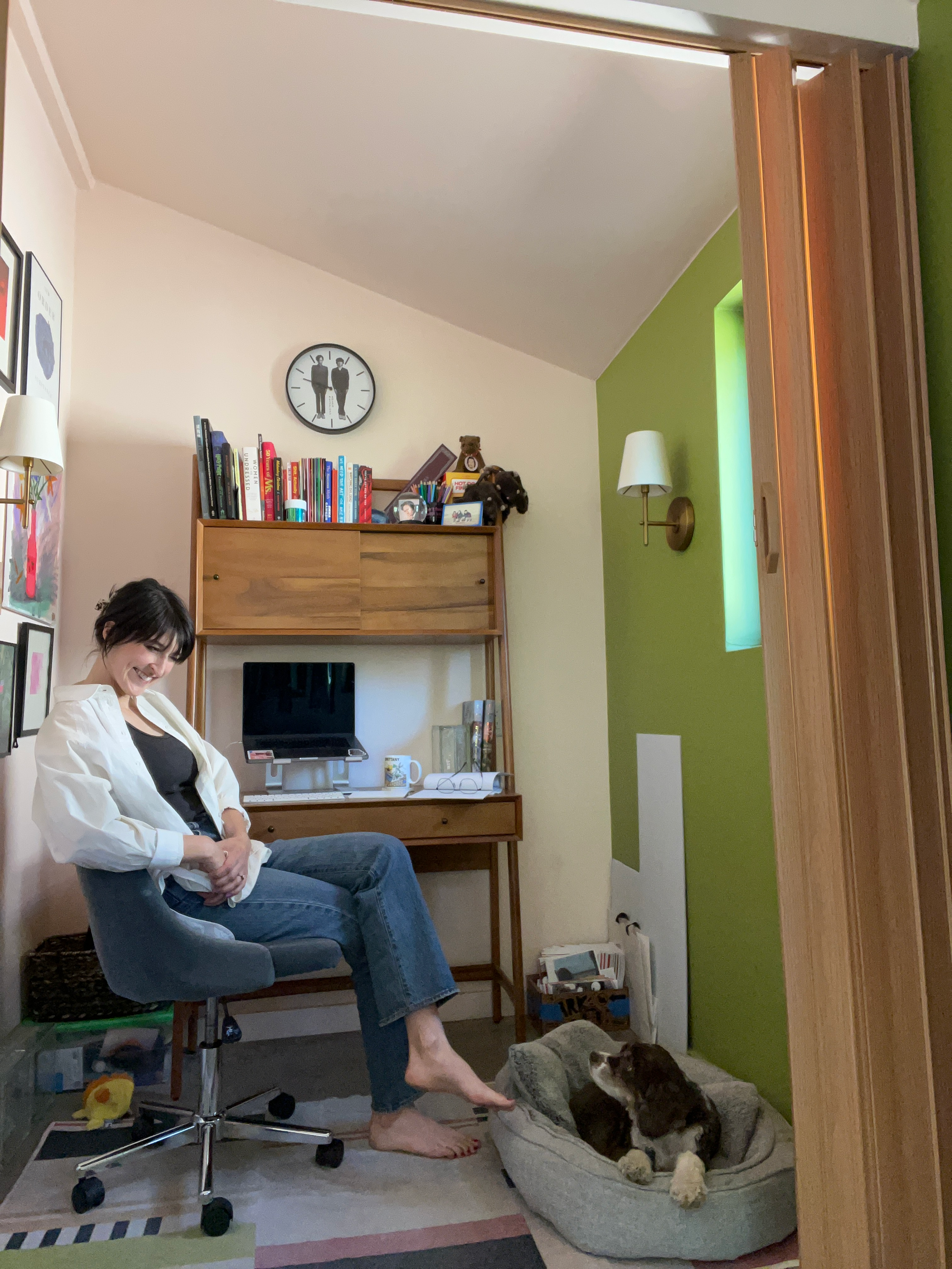 Portrait of Brittany Feenstra sitting at desk smiling at her dog