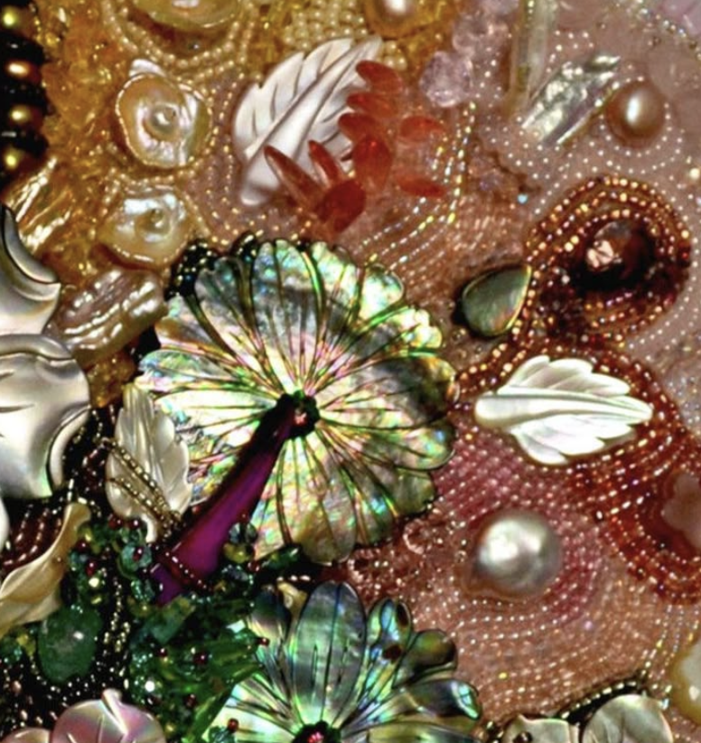 Close-up of colorful jewelry, including pearls, shells, beads, and iridescent stones, arranged in an intricate display.