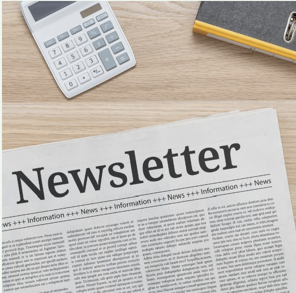 A newspaper titled 'Newsletter' on a wooden surface, with a calculator and a notebook nearby.