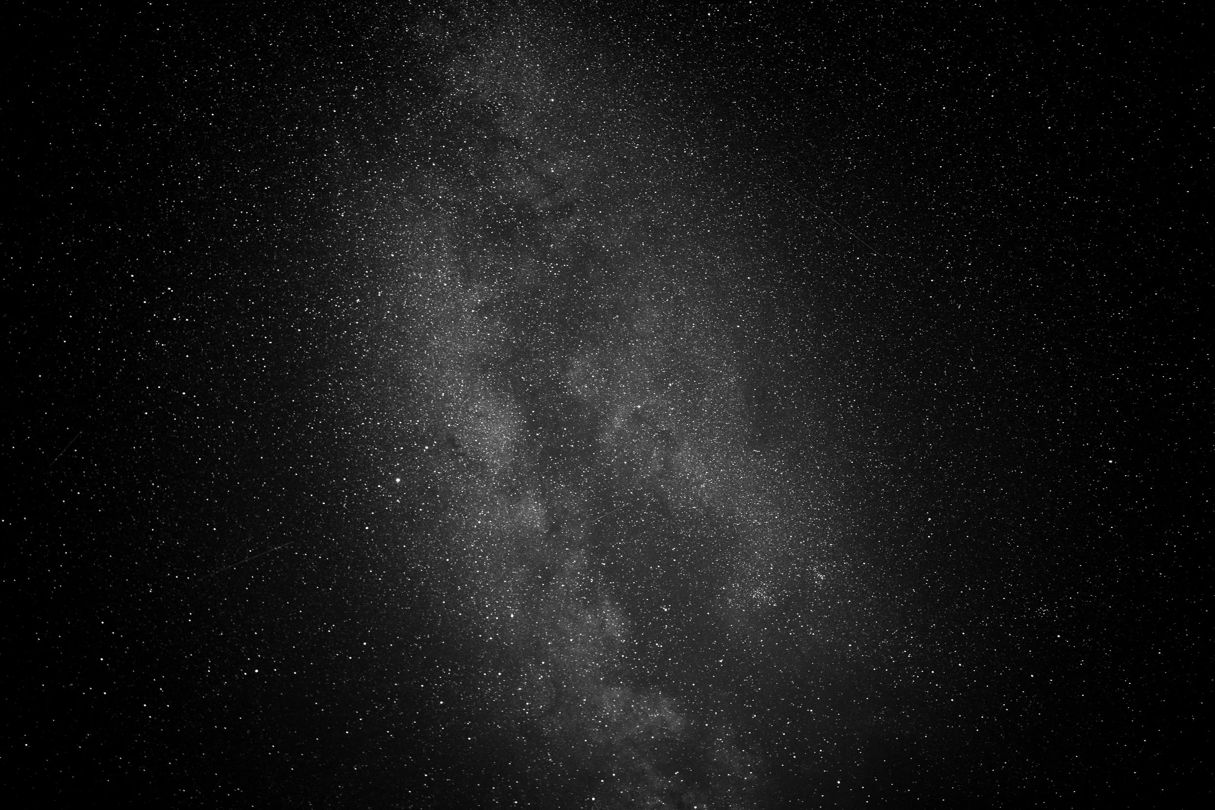 A clear night sky filled with countless stars and the Milky Way galaxy stretching diagonally across the image.