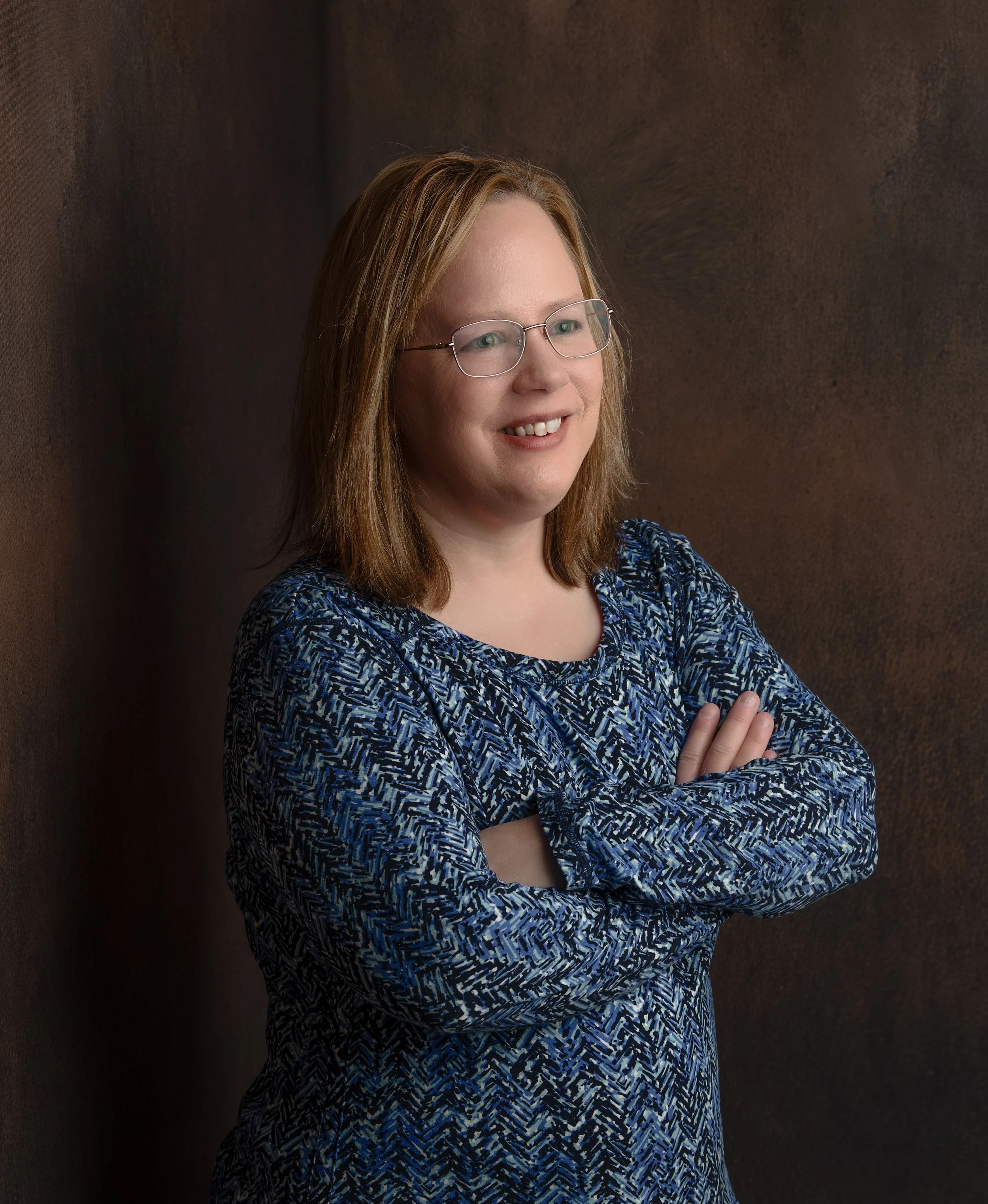 Certified Wayfinder Life Coach Kristin Enkvetchakul is standing in front of a dark background smiling warmly.