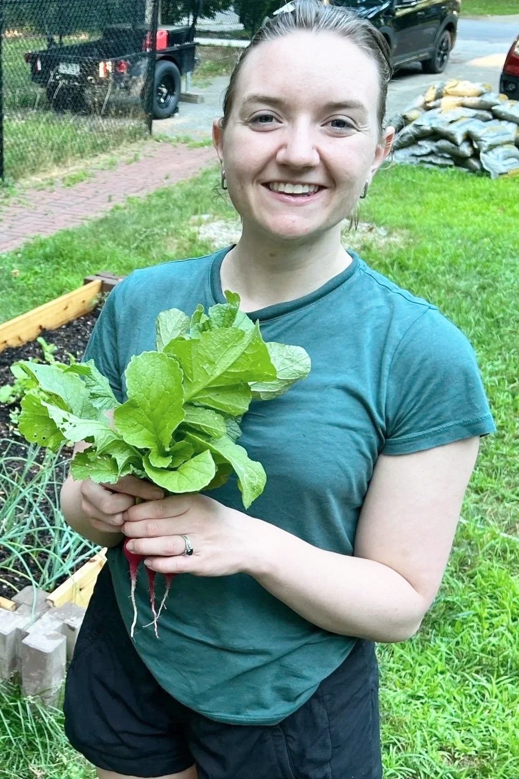 Professional home organizer harvesting radishes in a backyard vegetable garden.