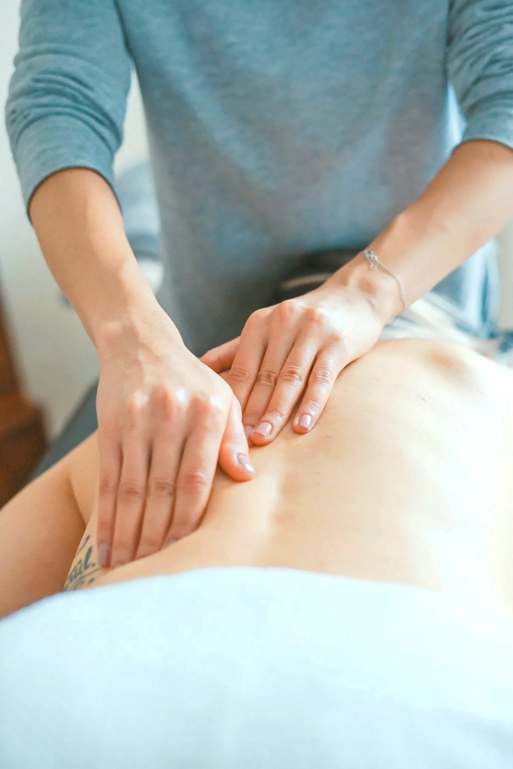 A person getting a massage, with hands applying pressure to the person's back.